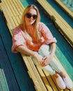 Portrait beautiful young blonde woman sitting on bench in a city park Royalty Free Stock Photo