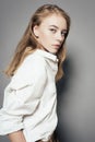 Portrait of a beautiful young blonde woman in a white shirt in the studio on a gray background