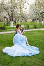 Portrait of beautiful young bride drinking champagne posing in the park or garden in blue dress outdoors on a bright Royalty Free Stock Photo