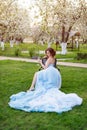 Portrait of beautiful young bride drinking champagne posing in the park or garden in blue dress outdoors on a bright Royalty Free Stock Photo