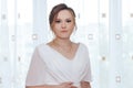 Portrait of a beautiful young bride in a white elegant wedding dress, standing at the window Royalty Free Stock Photo