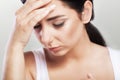 Portrait of a beautiful young brunette with bare shoulders, severe headaches, migraine, colds. The concept of treatment. Holds his Royalty Free Stock Photo