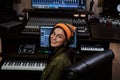 Portrait of beautiful young brunette, female artist smiling at camera while playing keyboard synthesizer, sitting in Royalty Free Stock Photo