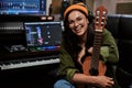 Portrait of beautiful young brunette, female artist smiling at camera while sitting with ukulele in recording studio Royalty Free Stock Photo