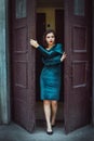 Portrait of beautiful young brunette woman stepping out the door of the old building Royalty Free Stock Photo