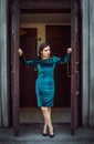 Portrait of beautiful young brunette woman stepping out the door of the old building Royalty Free Stock Photo