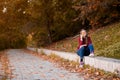 Portrait of beautiful young brunette woman in red shirt and jeans hiding eyes behind autumn leaves Royalty Free Stock Photo