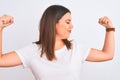 Portrait of beautiful and young brunette woman standing over isolated white background showing arms muscles smiling proud Royalty Free Stock Photo