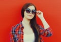 Portrait beautiful young brunette woman wearing a sunglasses in a city on red background Royalty Free Stock Photo