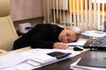 Portrait of a beautiful young business woman sleeping at her workplace in the office. Royalty Free Stock Photo