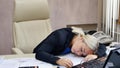 Portrait of a beautiful young business woman sleeping at her workplace in the office. Royalty Free Stock Photo