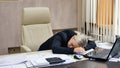 Portrait of a beautiful young business woman sleeping at her workplace in the office. Royalty Free Stock Photo