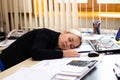 Portrait of a beautiful young business woman sleeping at her workplace in the office. Royalty Free Stock Photo