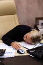 Portrait of a beautiful young business woman sleeping at her workplace in the office. Royalty Free Stock Photo