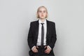 Portrait of a beautiful young business woman standing against grey background. Girl with short bob blonde hair wearing in suit and Royalty Free Stock Photo