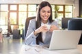 Portrait of beautiful young businesswoman drinking coffee and using laptop in office Royalty Free Stock Photo