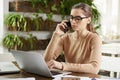 Attractive businesswoman making a call while sitting in front of laptop in the office and working Royalty Free Stock Photo