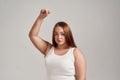 Portrait of a beautiful young caucasian plus size woman wearing white shirt, raising her arm, looking at camera while Royalty Free Stock Photo