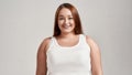 Portrait of a beautiful young caucasian plus size woman wearing white shirt, smiling at camera while posing isolated