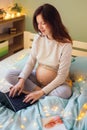 Active pregnant woman working on laptop on bed Royalty Free Stock Photo