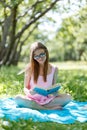 Beautiful young caucasian woman reading a book outdoor. Sitting on grass Royalty Free Stock Photo