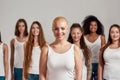 Portrait of beautiful young caucasian woman with shaved head in white shirt smiling at camera. Group of diverse women Royalty Free Stock Photo