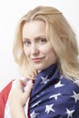 Portrait of beautiful young Caucasian woman wrapped in American flag against white background Royalty Free Stock Photo