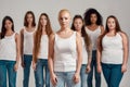 Portrait of beautiful young caucasian woman with shaved head in white shirt looking at camera. Group of diverse women Royalty Free Stock Photo