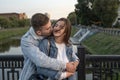 Portrait of beautiful young couple on the bridge. Guy gently embrace his beloved. Happy girl closed eyes. Romantic date Royalty Free Stock Photo