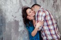 Portrait of beautiful young couple in casual clothes hugging and smiling, standing against gray wall Royalty Free Stock Photo