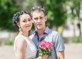 Portrait of beautiful young couple female bride with small wedding pink flowers roses bouquet and male bridegroom, smiling and loo