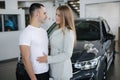 Portrait of beautiful young couple happy after buying new car from car showroom. Woman hug her man and smile. Elegant Royalty Free Stock Photo