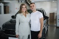 Portrait of beautiful young couple happy after buying new car from car showroom. Woman hus her man and glad Royalty Free Stock Photo