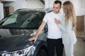Portrait of beautiful young couple happy after buying new car from car showroom. Woman hus her man and glad Royalty Free Stock Photo