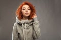 Portrait of a beautiful young curly-haired girl with fiery red hair looking at the camera on a gray background. Royalty Free Stock Photo