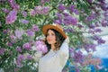 Portrait of beautiful young dark-haired woman with blue eyes in hat near the blooming. Happy model with curly hair. Spring Royalty Free Stock Photo