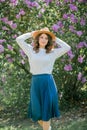 Portrait of beautiful young dark-haired woman with blue eyes in hat near the blooming. Happy model with curly hair. Spring Royalty Free Stock Photo