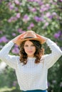 Portrait of beautiful young dark-haired woman with blue eyes in hat near the blooming. Happy model with curly hair. Spring Royalty Free Stock Photo