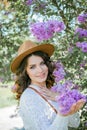 Portrait of beautiful young dark-haired woman with blue eyes in hat near the blooming. Happy model with curly hair. Spring Royalty Free Stock Photo