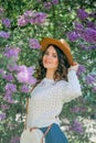 Portrait of beautiful young dark-haired woman with blue eyes in hat near the blooming. Happy model with curly hair. Spring Royalty Free Stock Photo