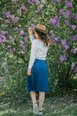 Portrait of beautiful young dark-haired woman with blue eyes in hat near the blooming. Happy model with curly hair. Spring Royalty Free Stock Photo