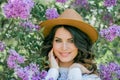 Portrait of beautiful young dark-haired woman with blue eyes in hat near the blooming. Happy model with curly hair. Spring Royalty Free Stock Photo