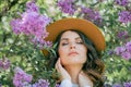 Portrait of beautiful young dark-haired woman with blue eyes in hat near the blooming. Happy model with curly hair. Spring Royalty Free Stock Photo