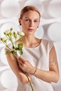 Portrait of a beautiful young disabled woman, born without an arm, holding a flower in her hands in a white dress Royalty Free Stock Photo