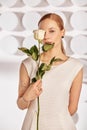 Portrait of a beautiful young disabled woman, born without an arm, holding a flower in her hands in a white dress Royalty Free Stock Photo