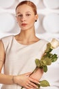 Portrait of a beautiful young disabled woman, born without an arm, holding a flower in her hands in a white dress Royalty Free Stock Photo