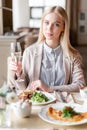 Portrait of a beautiful young elegant blonde woman in the cafe with a glass of champagne. Royalty Free Stock Photo