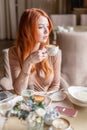 Nice redhead woman eat breakfast in cafe. Portrait of young charming female drinking coffee and toasted sandwich in Royalty Free Stock Photo