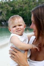 Portrait of beautiful young European mother hugging her little daughter on a background of tropical beach Royalty Free Stock Photo