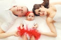 Portrait of beautiful young family mother, father with baby lying on bed or carpet together at home, top view Royalty Free Stock Photo